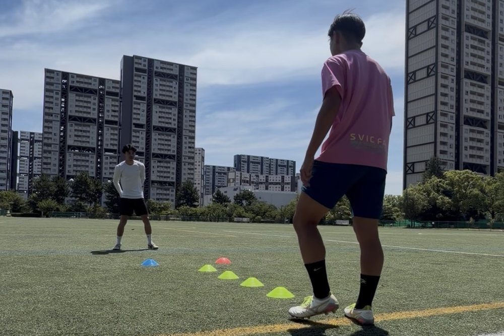 コーンを並べたグラウンドで向かい合ってトレーニングする様子